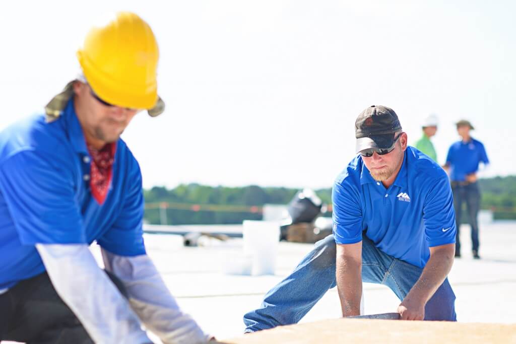 Mid-South Roof Systems Team Members atop a roof assessing a commercial roof