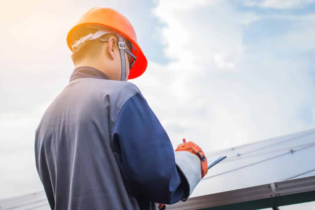 engineers operating and check generating power of solar power plant on solar rooftop; technician in industry uniform on level of job description at industrial
